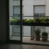 Huerto urbano en balcón de un piso con mesa de cultivo y macetas de hoja verde