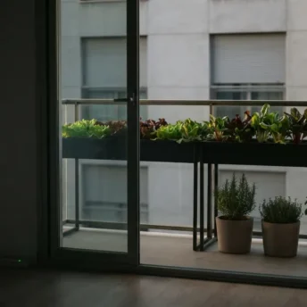 Huerto urbano en balcón de un piso con mesa de cultivo y macetas de hoja verde