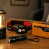 Linterna de emergencia, frontal, farol y radio de manivela alineados sobre una mesa oscura