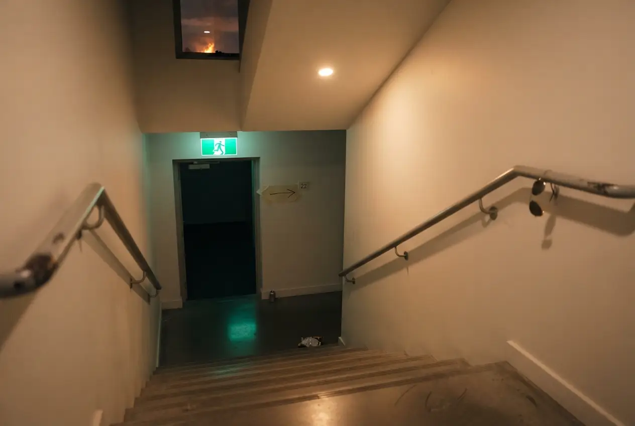 Escalera de emergencia de un edificio de viviendas con la señal verde de salida iluminada en el rellano